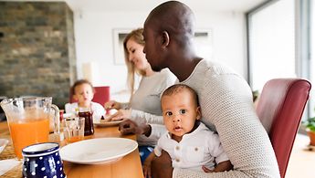 Vater, Mutter und zwei kleine Kinder am Frühstückstisch